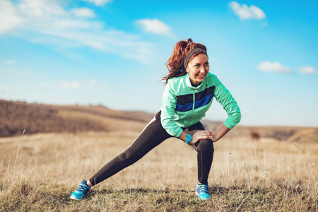 Young fitness woman doing stretching exercise after jogging in the nature.