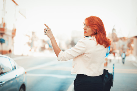Businesswoman standing by the street calling for Taxi.の写真素材
