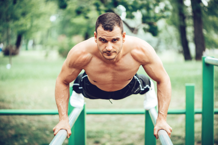 Young sportsman doing push-up exercise in the park. Looking at camera.の写真素材
