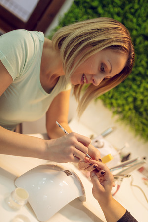 Happy beautician paint the nails of female clients at the beauty salon.の写真素材