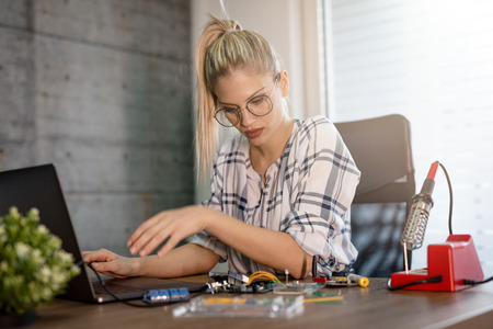 Young woman technician focused on the repair of electronic equipment cecking something on the laptop.の写真素材