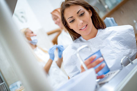 Beautiful young woman in visit at the dentist office preparing for checking up her teeths.の写真素材