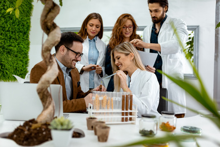 University colleague biologists taking experiment on sprout and checking the analysis of the sample of plant in the lab tube.の写真素材