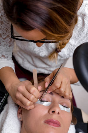 Beautician applying extended eyelashes to model. Top view.