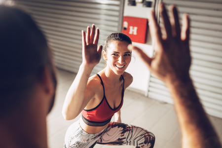 Young muscular smiling couple celebrating after successful hard workout at the garage gym and happy giving high five.の写真素材