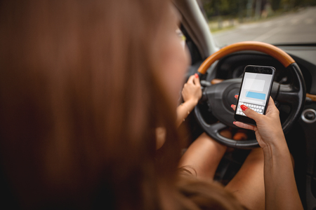 Woman texting on smartphone while driving a car.の写真素材