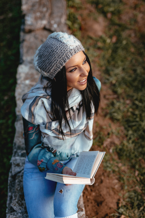 Top view of beautiful young woman enjoying in autumn colors sunny forest looking away and holding a...