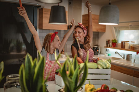 Happy mother and her daughter enjoy and having fun in making and having healthy meal together at their home kitchen.の写真素材