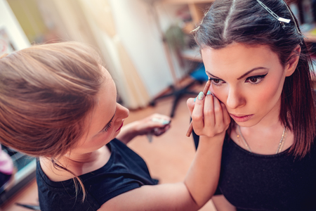 Make-up artist applying the eyeliner to model.の写真素材