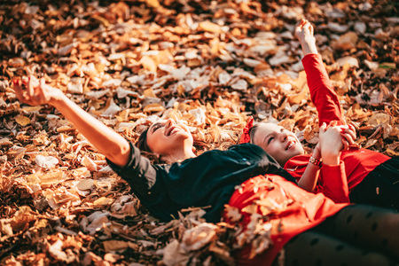 Beautiful young woman and her little daughter are enjoying in autumn sunny forest colors. They are...