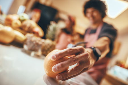 Close up on young man's hand holding mandarin in domestic kitchen.の写真素材