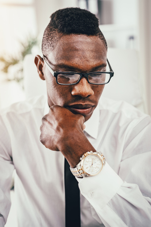 A portrait of a pensive African businessman, who is working in modern office.の写真素材