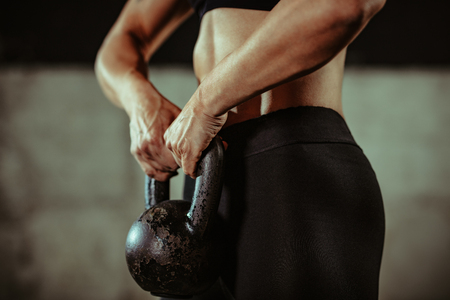 Close-up on a muscular hands ready to do exercise with kettlebell at the gym.の写真素材