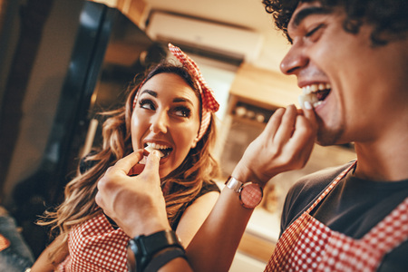 Happy young couple enjoys and having fun in eating slices of apple and making healthy meal together...