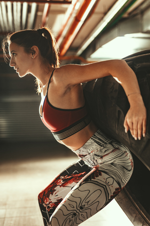 Young muscular woman is doing hard exercise with tire on cross fit training at the garage.の写真素材