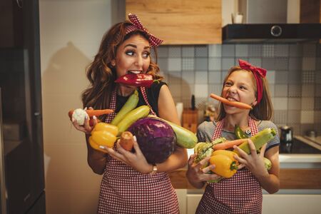 Happy mother and her daughter enjoy preparing for marinating vegetables and making healthy meal together with fun, at their home kitchen.の写真素材