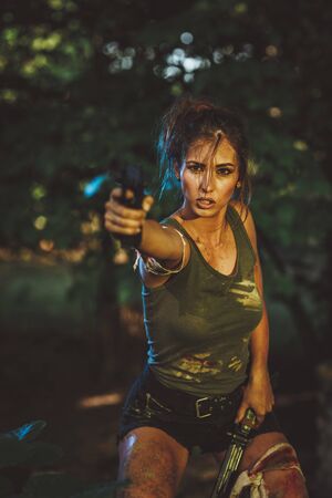Beautiful young woman holding gun and getting ready for the attack in abandoned ruin.