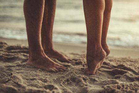 Loving couple is hugging and kissing on the sandy beach. Close-up of a couple's feet.の写真素材