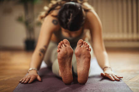 Young woman is doing yoga meditation in the living room at home. She is meditating on floor mat in morning sunshine.の写真素材