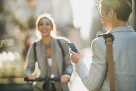Rear view of a mature business woman using a smartphone while going to work.の写真素材