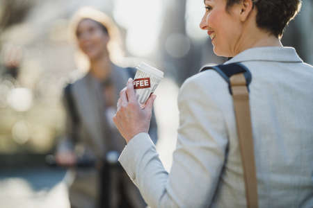 A mature business woman drinking coffee while go to work through the city.の写真素材