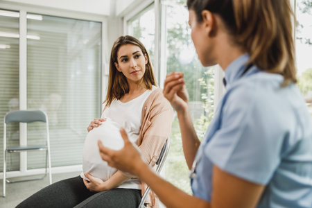 Attractive pregnant woman talking to nurse while waits for gynecologist check up.の写真素材
