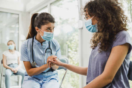 Nurse talking to African American female teenager and taking notes before vaccination against virus.の写真素材