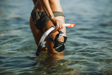 Close-up of an attractive woman with her scuba mask and snorkel walking through the sea after snorkeling.の写真素材