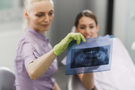 A female dentist and her young patient looking at orthopantomogram during dental appointment.の写真素材