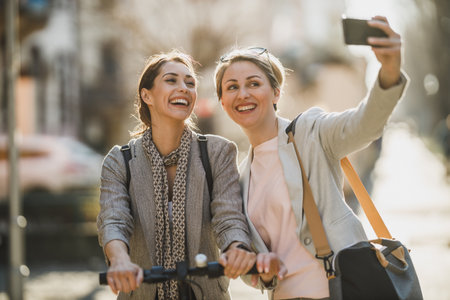 A two successful businesswomen taking a selfie with smartphone while walking through the city.の写真素材