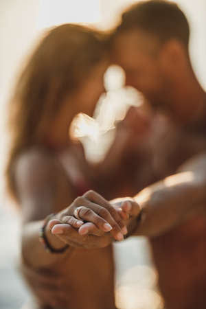Close-up shot of a loving couple holding hands and dancing together during spending summer vacation on a beach.の写真素材