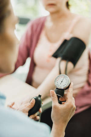 Close-up of a nurse checking the blood pressure to senior woman.の写真素材