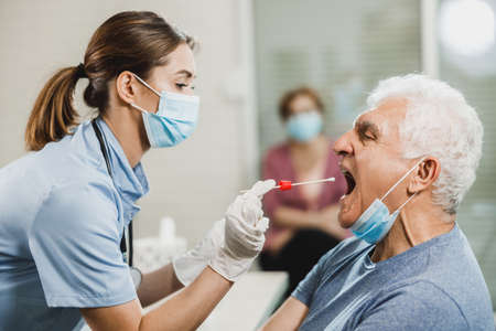 A senior man having swab medical test from throat during coronavirus pandemic.