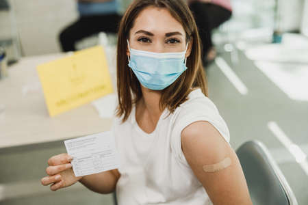 A pregnant woman showing vaccination certificate after receiving the Covid-19 vaccine. Looking at camera.の写真素材