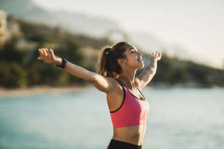 Young fit woman breathing with open arms and relaxing after her exercising near to sea.の写真素材