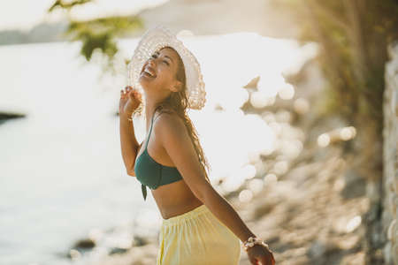 Young happy woman having fun and feeling playful while spending summer day at the shore.の写真素材
