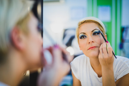 Portrait of a gorgeous woman applying a make up before the mirror at beauty salon.の写真素材