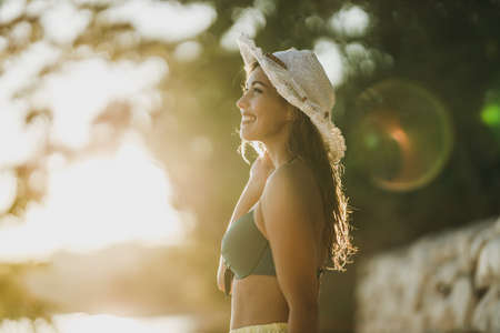 Carefree woman with sun hat going for a walk on the beach in summer day.の写真素材