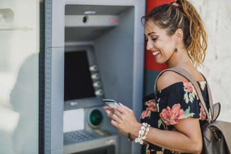 Side view of a woman while withdrawing money from ATM machine.の写真素材