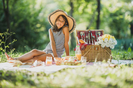 A cute smiling little girl spending a spring day in nature while enjoying picnic in the park.の写真素材