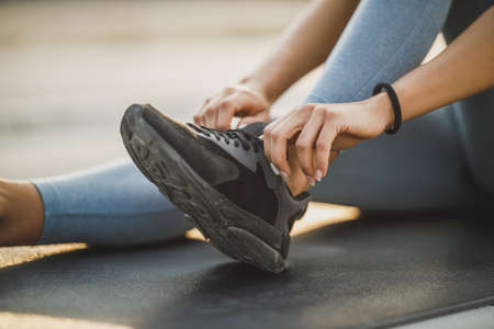 Close up shot of a female unrecognizable person tying their shoelaces while exercising.の写真素材
