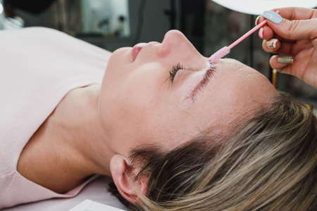 Close up of an unrecognizable makeup artist combs eyebrows with a micro brush after eyebrow lamination proces at the beauty salon.の写真素材