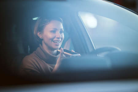 Portrait of a young beautiful happy woman with a nice smile driving a car talking at the smartphone.