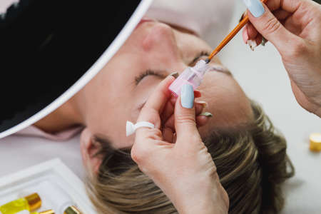 Close up of an unrecognizable beautician preparing model for eyebrow lamination procedure.の写真素材