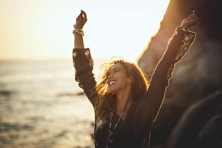 A beautiful young woman is having fun and relaxing on the beach at the sunset.