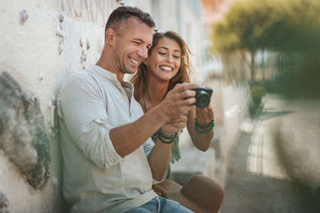 A beautiful young couple is having fun while walking around a Mediterranean town. They are enjoyed in summer sunny day, making photos for memories.の写真素材