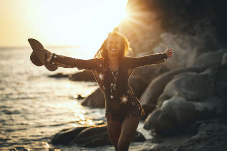 A beautiful young woman is having fun and relaxing on the beach at the sunset.の写真素材