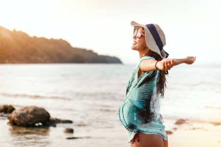 A beautiful young woman is relaxing on the beach in a sunny day. She is posing and looking at away...