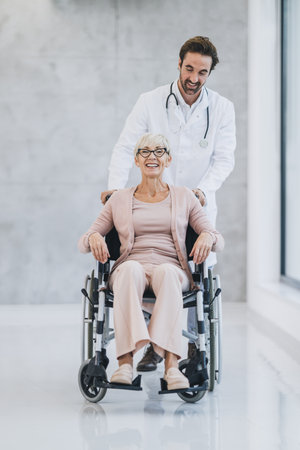 Shot of a young doctor pushing his senior wheelchair-bound woman patient and talking with her.の写真素材