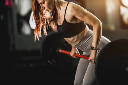 Shot of a muscular young woman doing row exercise with heavy weight for her back in the gym.の写真素材
